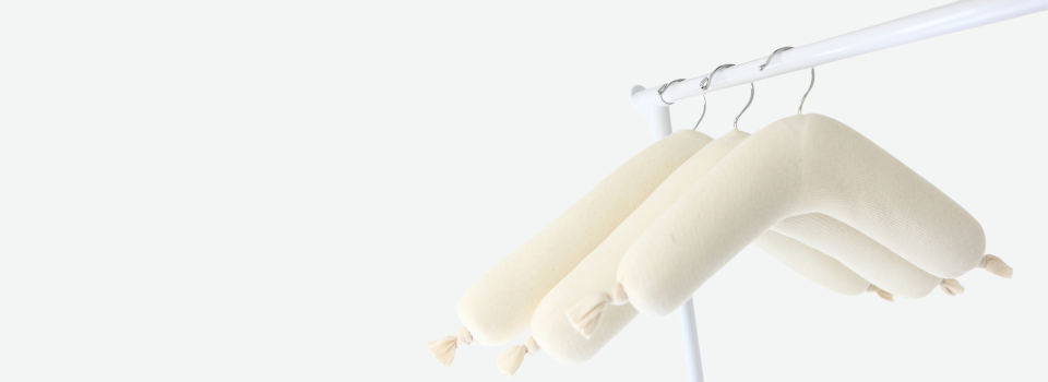 Hangerbee Padded Clothing Hangers on a rack. Our Museum quality hangers are perfect for the long term storage and preservation of garments of all sizes.