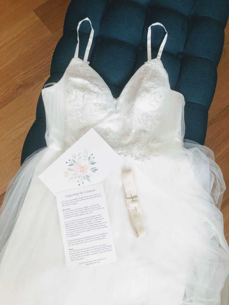 image featuring items in hangerbee padded hanger's save the dress, wedding dress preservation kit. The kit includes an heirloom safe, preservation quality padded clothes hanger, a large cotton garment bag, a large, zippered, cotton accessory bag and two small cotton drawstring bags, yards of cotton twill take, a wedding memories memory card, and instructions.