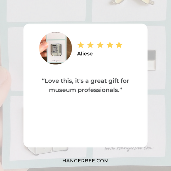 Positive review of Hangerbee padded hanger's Collections Toolbox Lapel Pin of a hygrothermograph pin on a  card that's designed to look like an acid-free box lined with ethafoam. The card is on a small, cotton bag which is on a wood table.