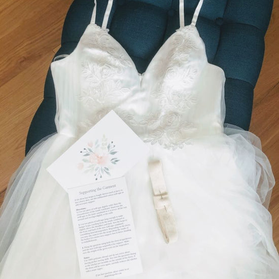 image featuring items in hangerbee padded hanger's save the dress, wedding dress preservation kit. The kit includes an heirloom safe, preservation quality padded clothes hanger, a large cotton garment bag, a large, zippered, cotton accessory bag and two small cotton drawstring bags, yards of cotton twill take, a wedding memories memory card, and instructions.