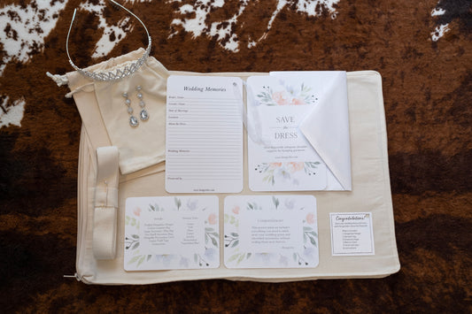 image featuring items in hangerbee padded hanger's save the dress, wedding dress preservation kit. The kit includes an heirloom safe, preservation quality padded clothes hanger, a large cotton garment bag, a large, zippered, cotton accessory bag and two small cotton drawstring bags, yards of cotton twill take, a wedding memories memory card, and instructions.