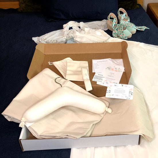 image featuring items in hangerbee padded hanger's save the dress, wedding dress preservation kit. The kit includes an heirloom safe, preservation quality padded clothes hanger, a large cotton garment bag, a large, zippered, cotton accessory bag and two small cotton drawstring bags, yards of cotton twill take, a wedding memories memory card, and instructions.