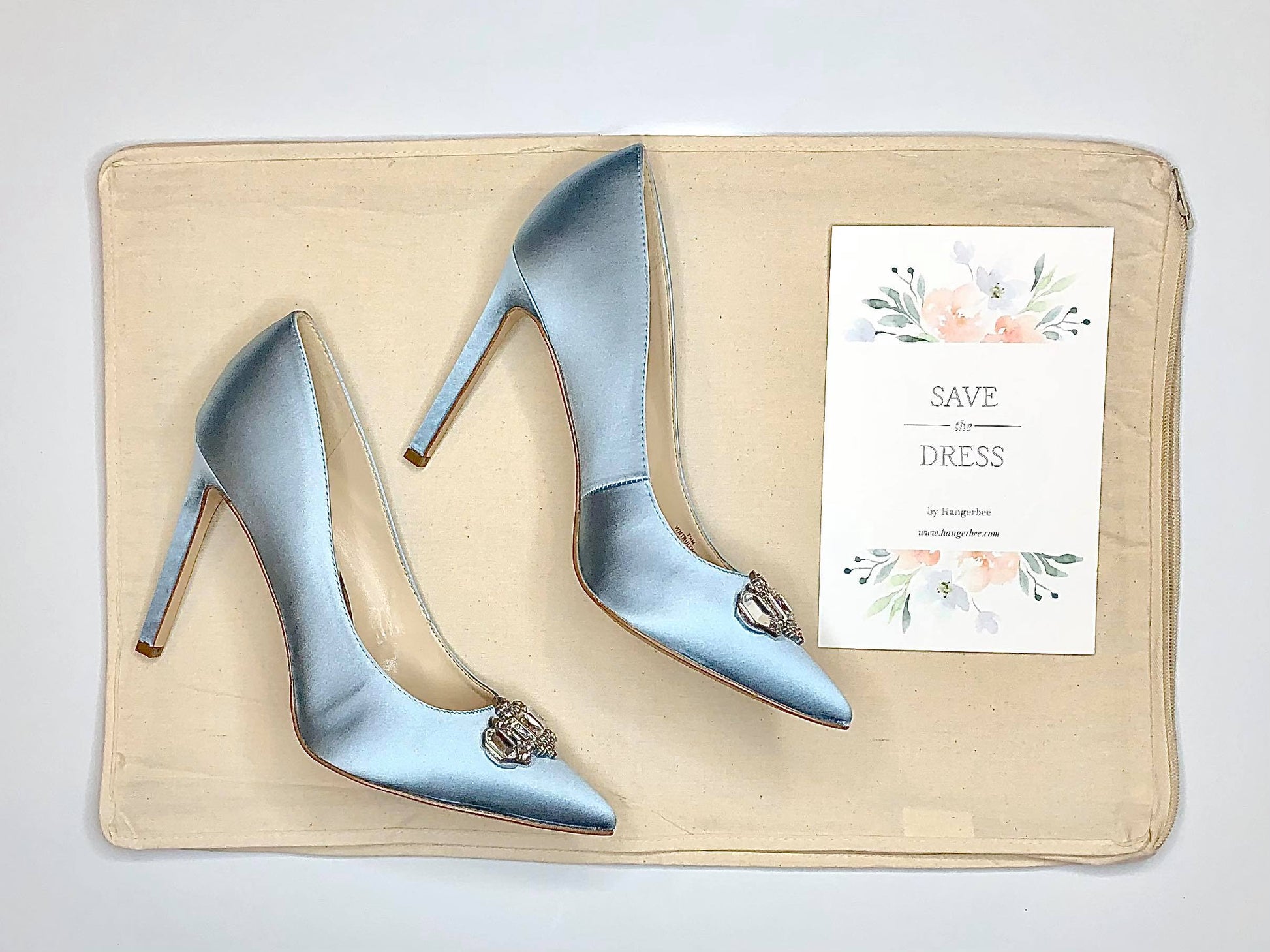 image featuring items in hangerbee padded hanger's save the dress, wedding dress preservation kit. The kit includes an heirloom safe, preservation quality padded clothes hanger, a large cotton garment bag, a large, zippered, cotton accessory bag and two small cotton drawstring bags, yards of cotton twill take, a wedding memories memory card, and instructions.