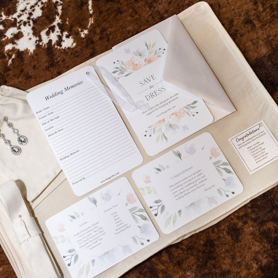 image featuring items in hangerbee padded hanger's save the dress, wedding dress preservation kit. The kit includes an heirloom safe, preservation quality padded clothes hanger, a large cotton garment bag, a large, zippered, cotton accessory bag and two small cotton drawstring bags, yards of cotton twill take, a wedding memories memory card, and instructions.